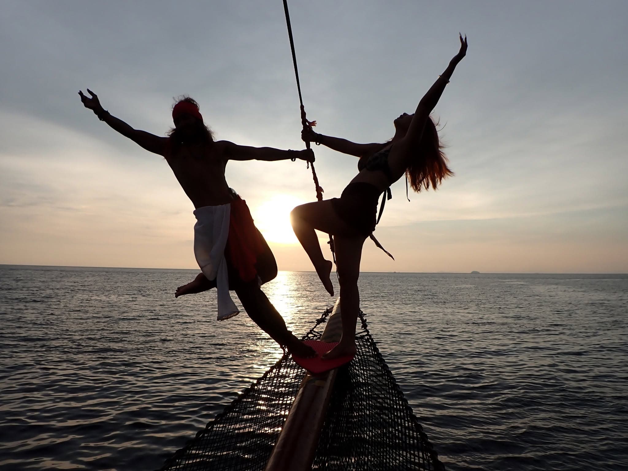 A pirate and a guest silhouetted on the bow of the Pirate Boat at sunset